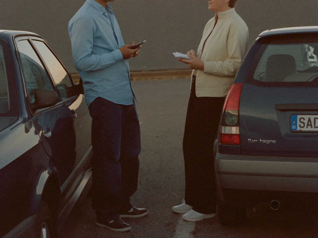 Two drivers calmly exchange information beside their parked cars.