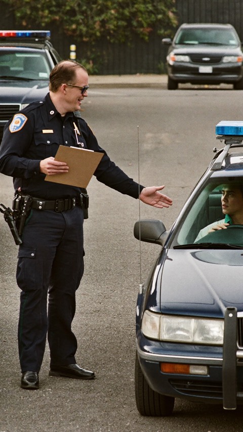Video poster: an officer with a clipboard speaks calmly with a driver.